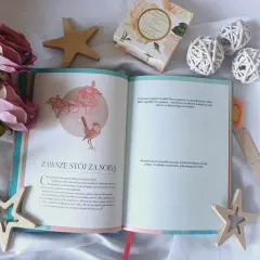 Otwarta książka z cytatem "Zawsze stój za sobą" i dekoracjami. Inspiracja, jak naprawić swoje życie, zaczyna się od wiary w siebie.