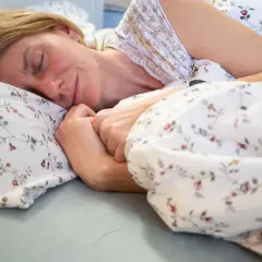 Kobieta śpi spokojnie, otulona pościelą w kwiaty. Czyżby znała sekret, jak szybko zasnąć?