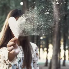 Dziewczyna w lesie trzyma serce, które rozpada się w pył. Jak zapomnieć o kimś, kto mi się podoba?