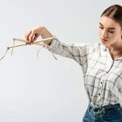 Kobieta trzyma drewniany krzyżak marionetki, ukazując słabe punkty manipulatora.