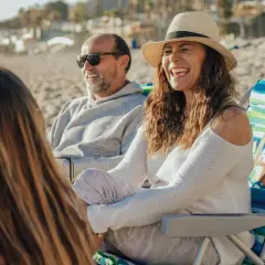 Rodzina na plaży, śmiejąca się i rozmawiająca. Może to być inspiracja, jak dotrzeć do dorosłego syna, budując wspólne wspomnienia.