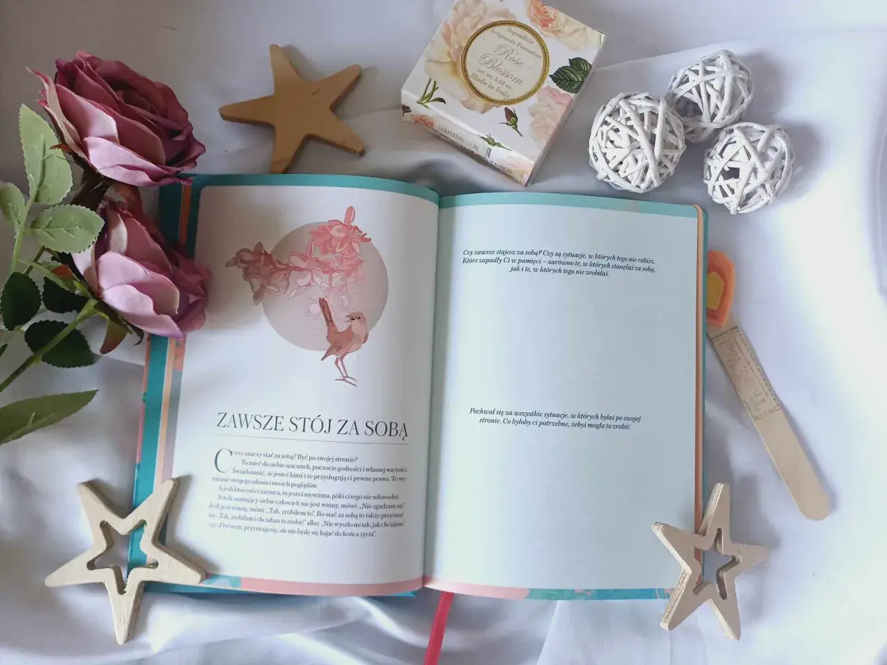 Otwarta książka z cytatem "Zawsze stój za sobą" i dekoracjami. Inspiracja, jak naprawić swoje życie, zaczyna się od wiary w siebie.