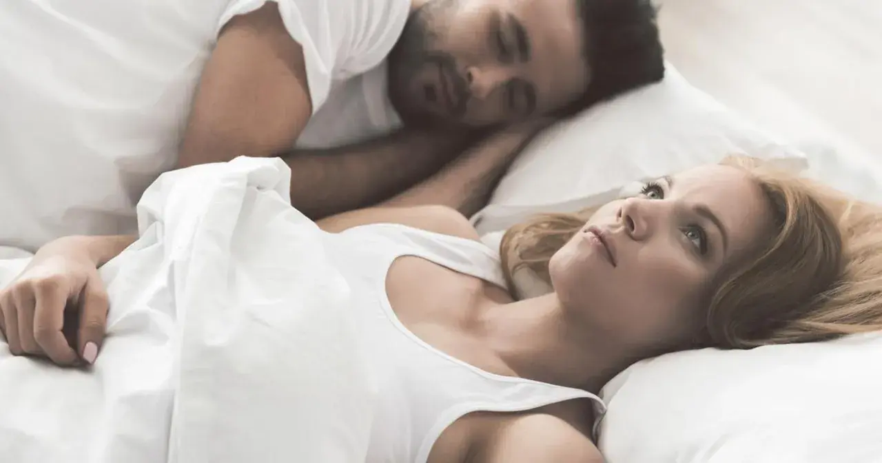 Kobieta leży obok śpiącego partnera, czując się jak sparaliżowana sennie.