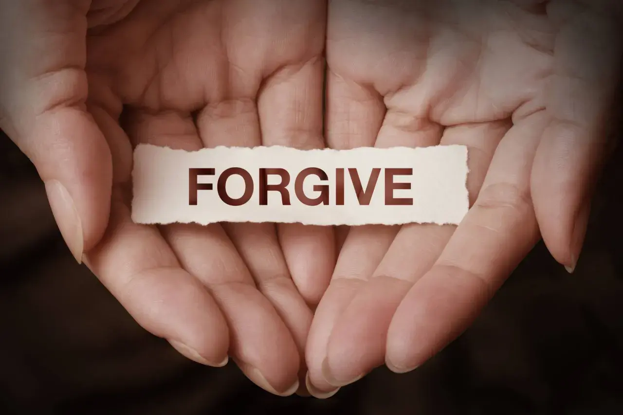 Dłonie trzymające skrawek papieru z napisem "FORGIVE". To symbol tego, co to znaczy wybaczyć – uwolnić się od urazy i otworzyć na pojednanie.