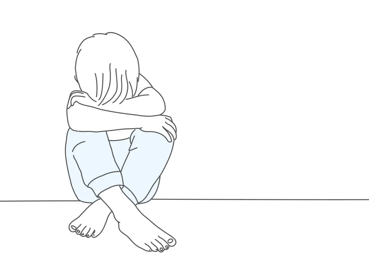 Smutne dziecko skulone na podłodze. Psychologia oceniająca innych często prowadzi do poczucia izolacji i smutku.